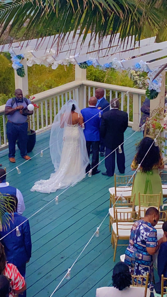 A wedding ceremony beneath the flower-draped pergola at A Stone's Throw Away