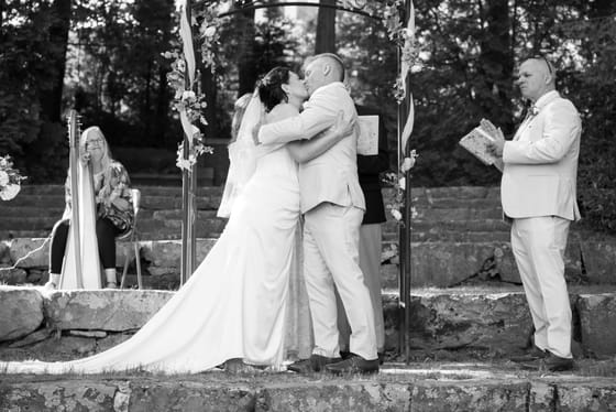 The first kiss beneath a floral arch, with a harpist playing, at Hartstone Inn