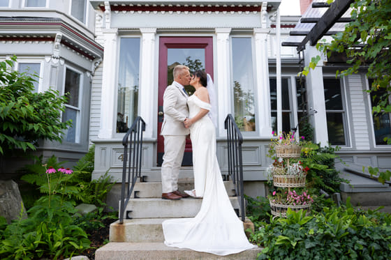 A couple kissing outside the Victorian entrance of Hartstone Inn