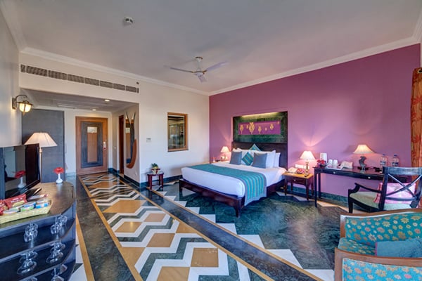 Deluxe Room: guest room with double bed, purple accent wall, seating and patterned marble floor