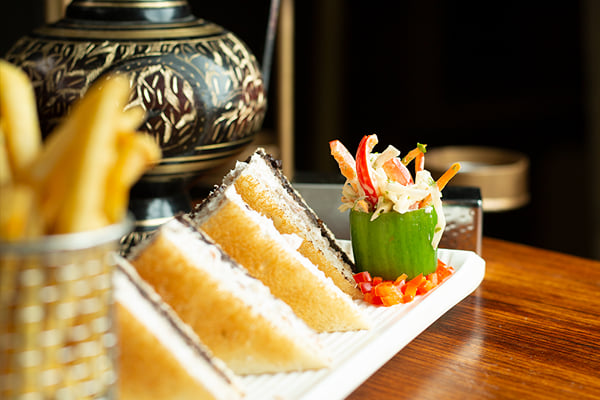 Food: close view of sandwich triangles, fries in a basket and a garnished cucumber cup