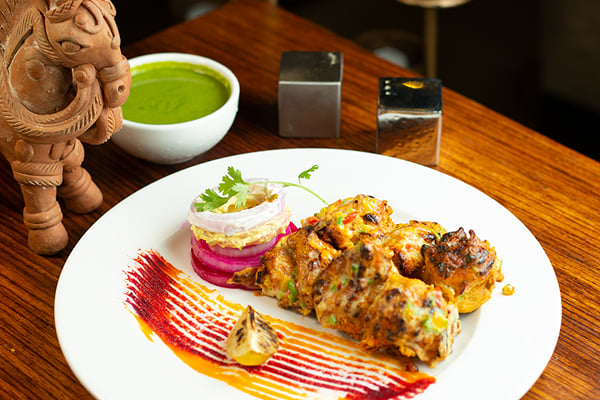 Food: grilled tikka pieces with green chutney, pickled onion and a terracotta elephant figure