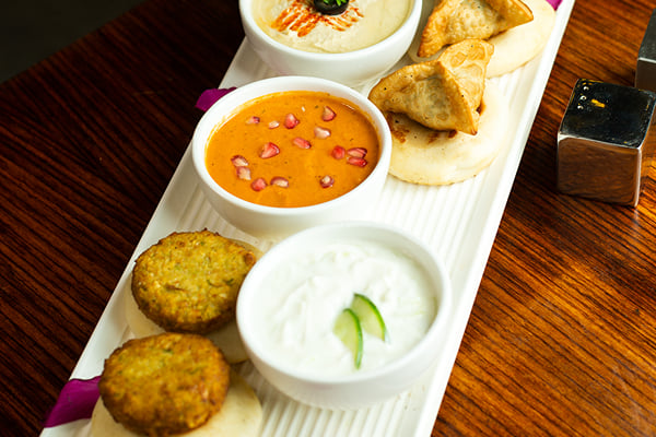 Food: overhead view of platter with dips, fritters and fried pastries on a wooden table