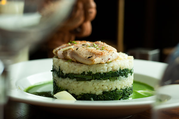Food: side view of layered rice and spinach tower topped with seared fish