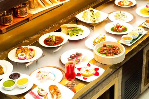 Food: buffet counter display with many plated dishes, dips and a glass of red drink