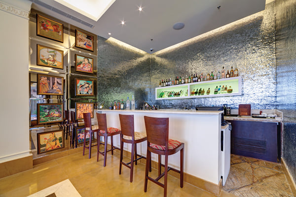 Liquid Lounge: bar counter with wooden stools, lit bottle shelf, textured wall and framed paintings