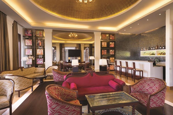 Liquid Lounge: lounge with red sofa, patterned armchairs and glass coffee table, bar counter behind