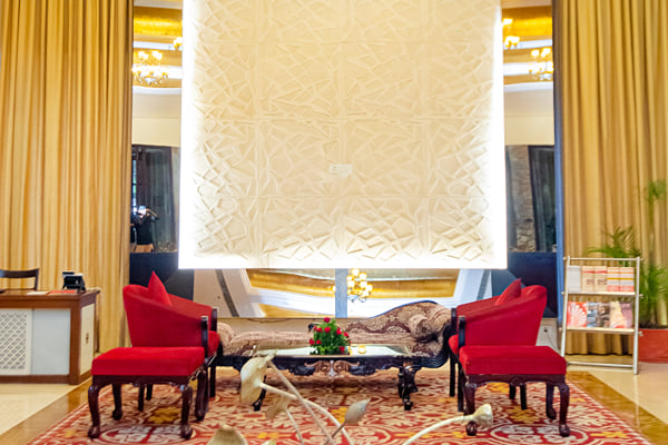 Lobby: lobby seating with red chairs, carved white wall panel, gold ceiling and metal sculpture