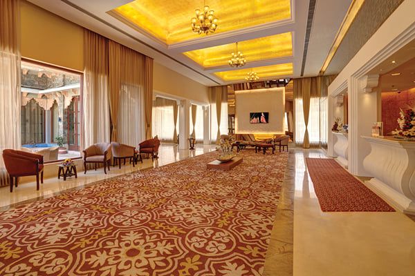 Lobby: wide lobby with patterned red carpet, lit ceiling panels, seating and curtained windows