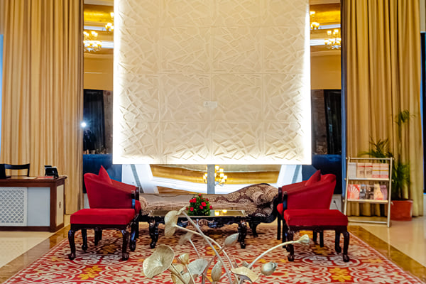 Lobby: lobby seating with red chairs, carved white panel and metal lotus sculpture in foreground