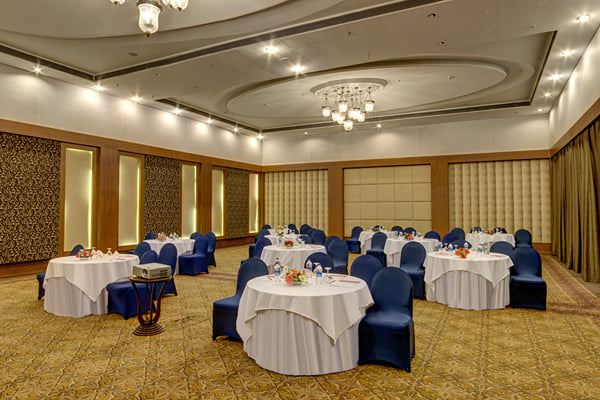 Meridian hall: banquet hall with round tables, white linen and navy chairs, projector on stand