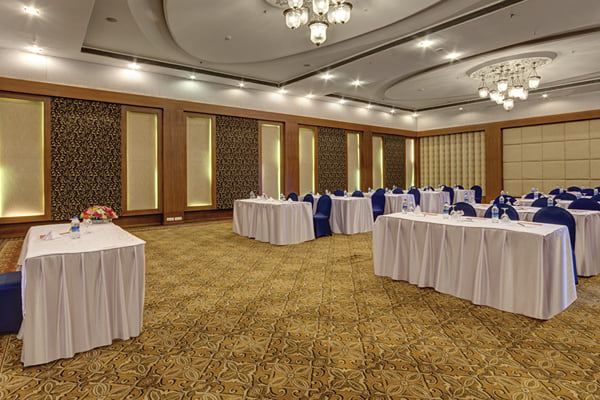 Meridian hall: banquet hall with long white tables, navy chairs and chandeliers, wide crop