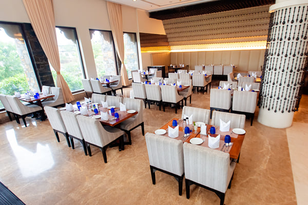 Myra restaurant: restaurant dining area with upholstered chairs, set tables, window curtains and decorated pillar