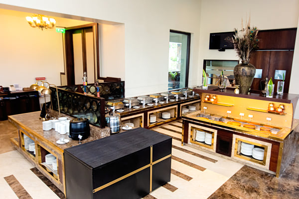 Myra restaurant: buffet counters with stacked plates, dining area and doorway in background