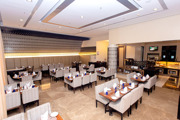 Myra restaurant: wide view of restaurant with set tables, striped chairs and buffet at far right