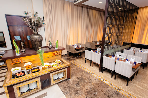 Myra restaurant: buffet counter with dishes and screen divider, dining tables and chairs at right