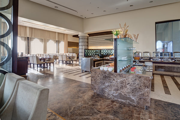 Myra restaurant: restaurant with marble buffet counter, chairs in foreground and dining area beyond