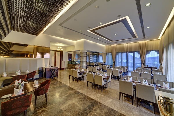 Myra restaurant: restaurant interior with set tables, chairs, glass window wall and buffet counter at right