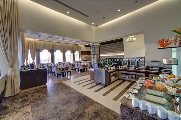 Myra restaurant: buffet counter with food trays, fruit and bowls, dining area with curtains behind