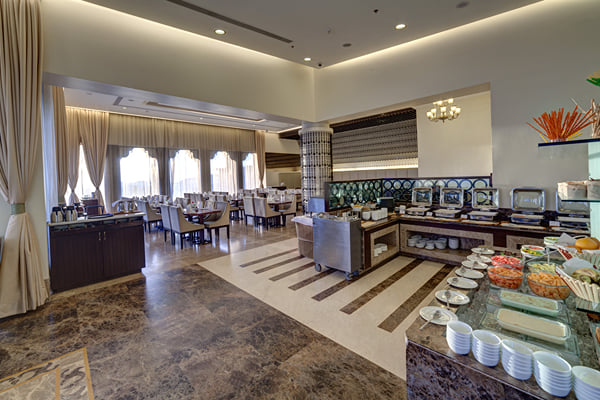 Myra restaurant: buffet counter with food trays and bowls, dining area with curtained windows behind