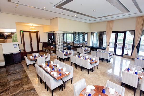 Myra restaurant: restaurant dining hall with set tables, upholstered chairs, wooden doors and glass doors