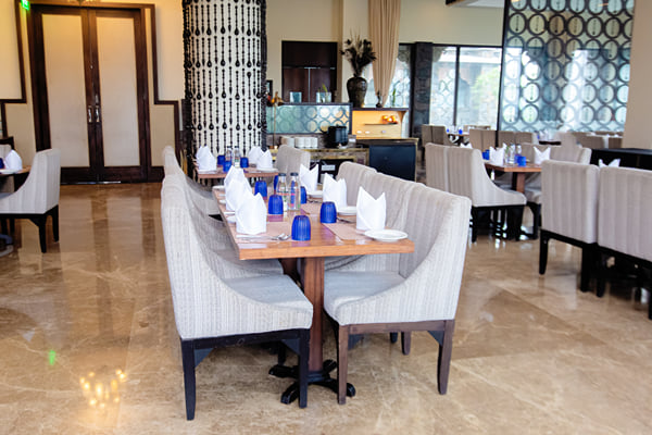 Myra restaurant: set dining table with upholstered chairs beside a patterned pillar and wooden doors