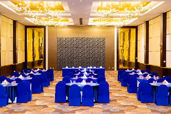 Panghat hall: large hall with chandeliers, round navy-cloth tables, blue chairs and patterned back wall
