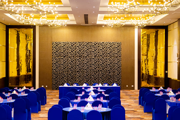 Panghat hall: large hall with chandeliers, round tables, blue chair covers and patterned back wall
