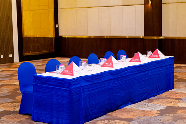 Panghat hall: long head table with blue cloth and Ramada tent cards, blue chairs in a hall