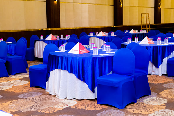 Panghat hall: round tables with blue cloths, blue chair covers and tent cards in a hall