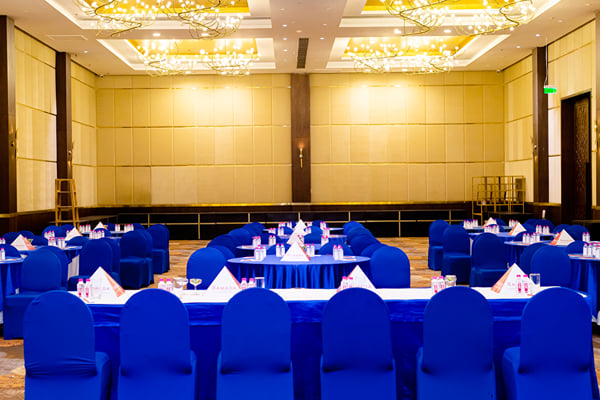 Panghat hall: hall with rows of blue-covered chairs and tables, chandeliers and wall panelling