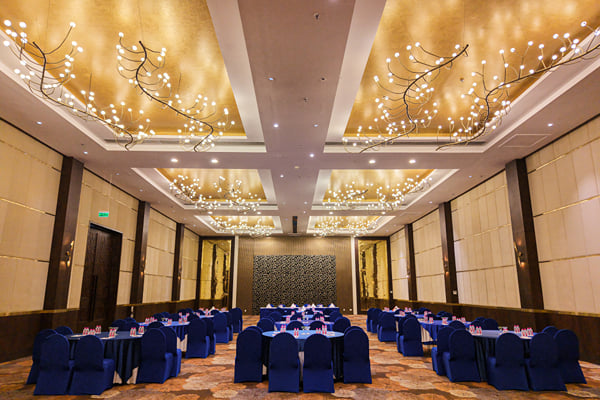 Panghat hall: wide view of banquet hall set with round tables under multiple chandeliers
