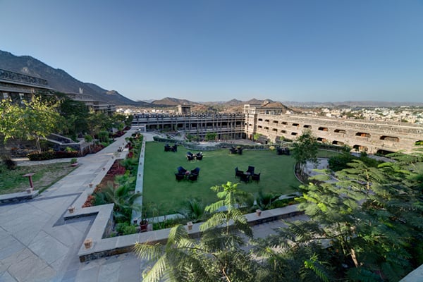 The resort: aerial view of green lawn with seating, pathways, trees, mountains and resort buildings