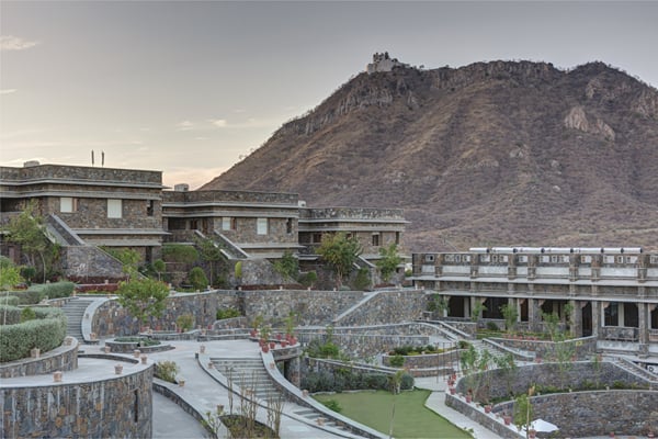 The resort: stone resort buildings and terraces below a rocky hill topped with a fort