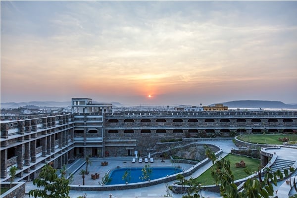 The resort: resort building and pool at sunset with garden lawn and sun on horizon