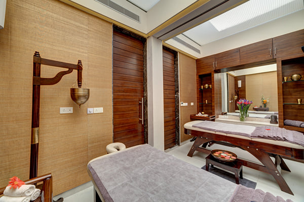 Sansha spa: spa room with two massage tables, wood panelling, a mirror and flowers