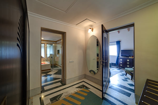 Suite: hallway with oval mirror and doors leading to a bathroom and a bedroom