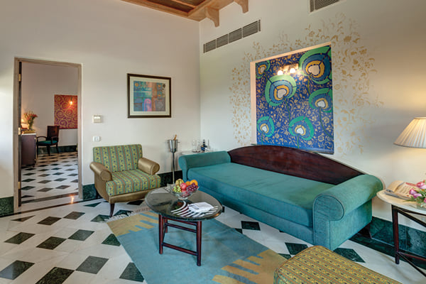 Suite: sitting room with teal sofa, peacock painting, green armchair and coffee table