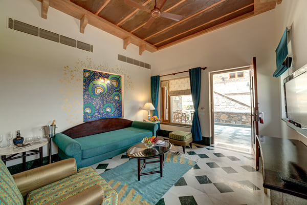 Suite: living area with teal sofa, painting and balcony door opening to terrace