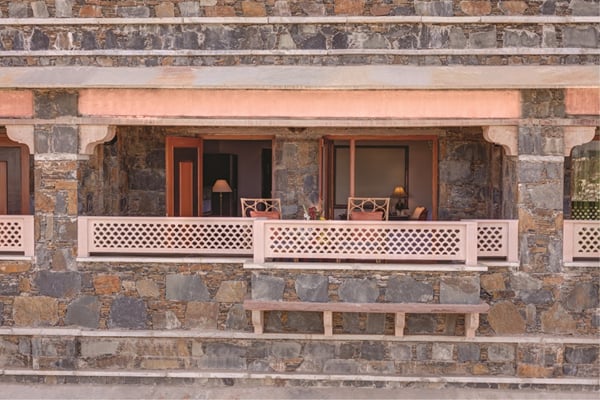 Super Deluxe Room: stone building facade with a wooden balcony railing and rooms behind