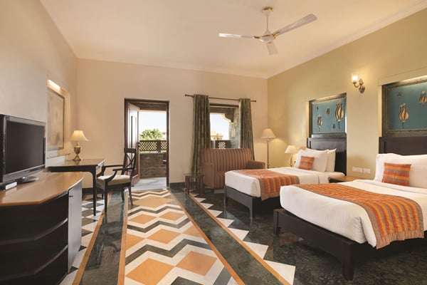 Super Deluxe Room: twin beds with orange runners, writing desk, television and patterned floor