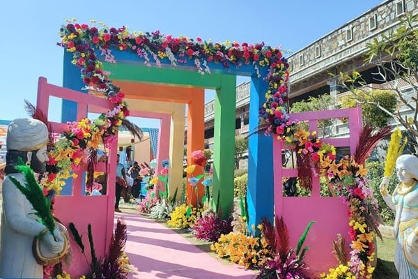 Wedding celebration: colourful painted arch gateway with flower garlands over a pink carpet path