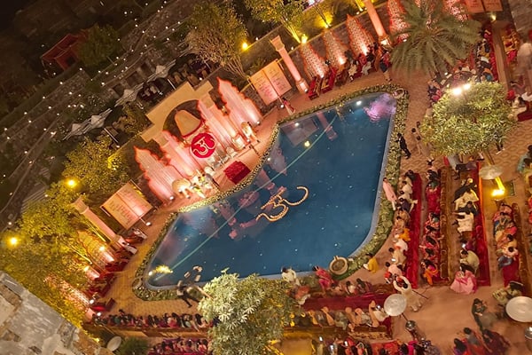 Wedding celebration: aerial view of pool with stage decor and seated guests at night