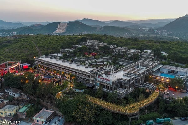 Wedding celebration: aerial dusk view of resort buildings on a wooded hillside with mountains