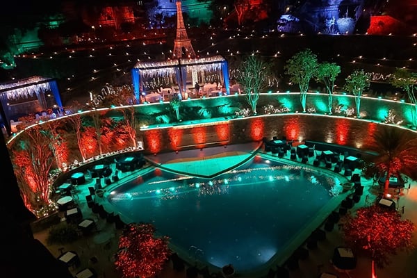 Wedding celebration: night aerial view of pool with Eiffel tower decor, green and orange lighting