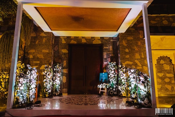 Wedding celebration: entrance with flower-decorated pillars and wooden doors in stone wall at night
