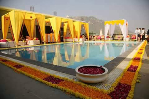 Wedding celebration: poolside cabanas with yellow drapes and marigold border near mountains