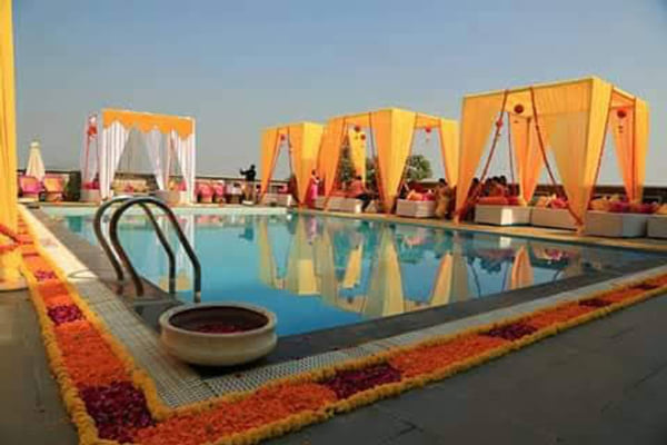 Wedding celebration: poolside cabanas with yellow drapes and marigold border at sunset