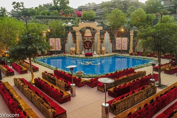 Wedding celebration: aerial view of pool with decorated stage and rows of red sofas for guests