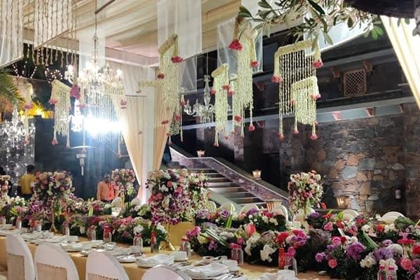 Wedding celebration: night banquet table with flowers, hanging drapes and stone steps in background